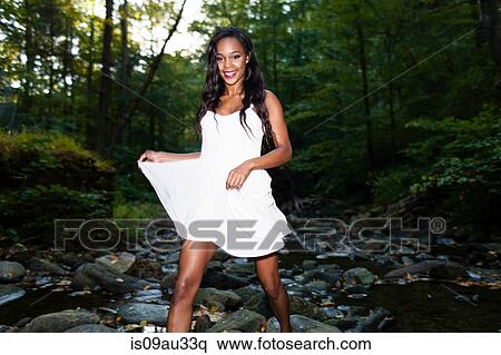 Stock Photography - Portrait of glamorous young woman stepping over forest river rocks. Fotosearch