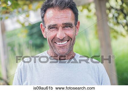 Stock Image - Portrait of mature man with stubble looking at camera smiling. Fotosearch