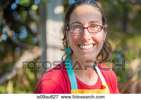 Portrait of mature woman wearing apron and glasses looking at camera smiling View Large Photo Image Stock Photo - Portrait of mature woman wearing apron and glasses looking at camera smiling. Fotosearch