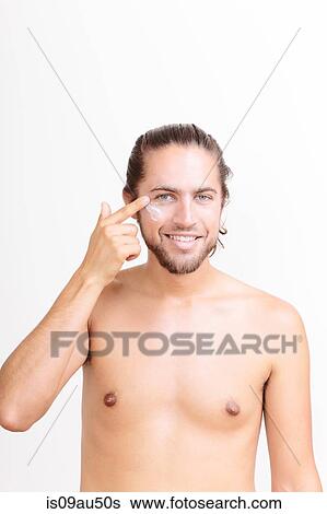 Portrait of young man applying moisturiser View Large Photo Image Stock Photograph - Portrait of young man applying moisturiser. Fotosearch