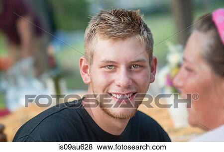 Portrait of young man at social gathering looking at camera smiling View Large Photo Image Stock Photo - Portrait of young man at social gathering looking at camera smiling. Fotosearch