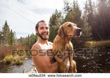 Portrait of young man carrying his wet dog at river, Lake Tahoe, Nevada, USA View Large Photo Image Picture - Portrait of young man carrying his wet dog at river, Lake Tahoe, Nevada, USA. Fotosearch