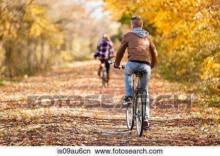Rear view of teenage boy and adult sister cycling in autumn forest View Large Photo Image Picture - Rear view of teenage boy and adult sister cycling in autumn forest. Fotosearch