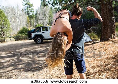 Rear view of young man carrying girlfriend over shoulder at forest campsite, Lake Tahoe, Nevada, USA View Large Photo Image Stock Photography - Rear view of young man carrying girlfriend over shoulder at forest campsite, Lake Tahoe, Nevada, USA. Fotosearch