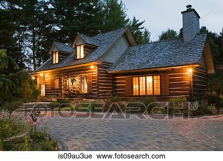 Stock Image - Reconstructed 1976 cottage style log home facade at dusk, Quebec, Canada. Fotosearch