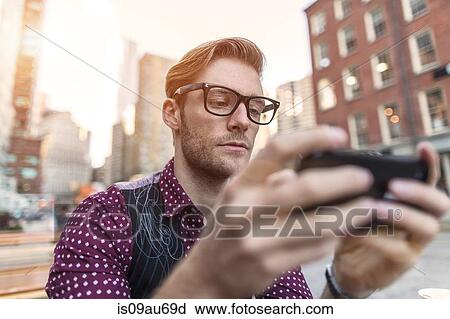 Serious young businessman reading smartphone text at sidewalk cafe, New York, USA View Large Photo Image Stock Image - Serious young businessman reading smartphone text at sidewalk cafe, New York, USA. Fotosearch