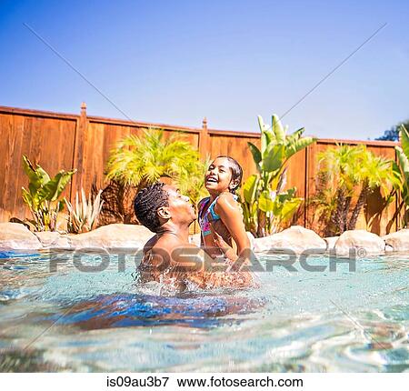Side view of father lifting up smiling daughter in swimming pool View Large Photo Image Stock Photo - Side view of father lifting up smiling daughter in swimming pool. Fotosearch