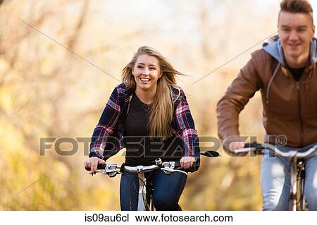Stock Image - Teenage boy and adult sister cycling through autumn forest. Fotosearch