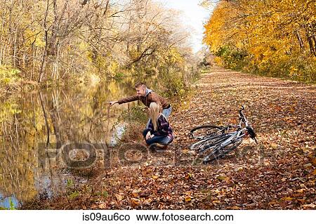 Teenage boy and adult sister pointing at river in autumn forest View Large Photo Image Picture - Teenage boy and adult sister pointing at river in autumn forest. Fotosearch