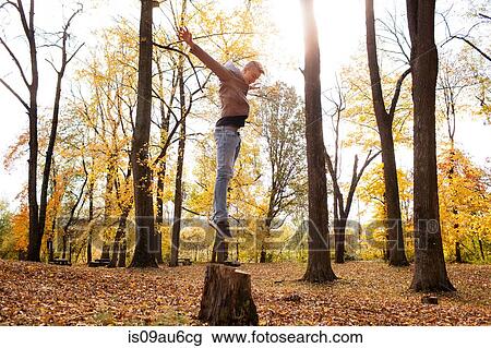 Teenage boy jumping on tree stump in autumn forest View Large Photo Image Stock Image - Teenage boy jumping on tree stump in autumn forest. Fotosearch