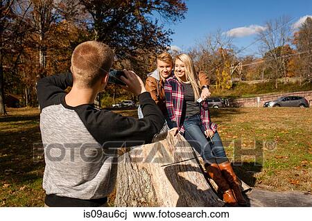 Teenage boy photographing brother and adult sister in autumn park View Large Photo Image Stock Image - Teenage boy photographing brother and adult sister in autumn park. Fotosearch