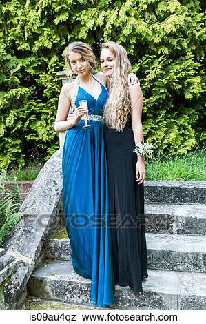 Teenage girls wearing prom dresses holding champagne flute looking at camera smiling View Large Photo Image Stock Photo - Teenage girls wearing prom dresses holding champagne flute looking at camera smiling. Fotosearch