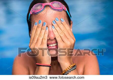 Stock Image - Teenager covering face in swimming pool. Fotosearch