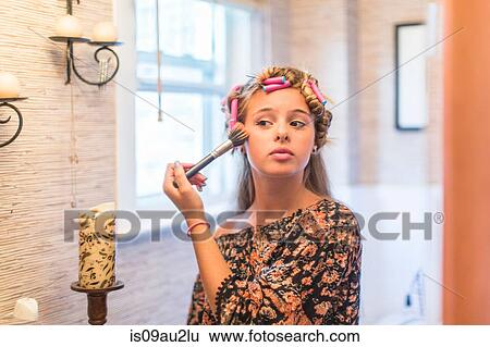 Stock Photograph - Teenager putting on make-up in bathroom. Fotosearch