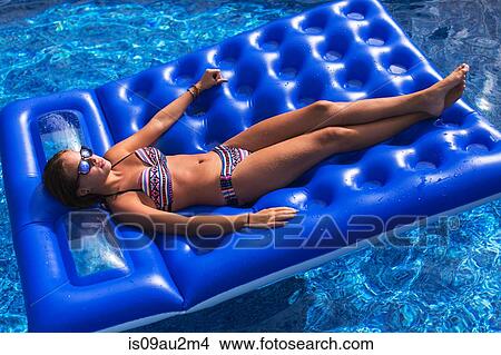 Teenager relaxing on inflatable in swimming pool View Large Photo Image Picture - Teenager relaxing on inflatable in swimming pool. Fotosearch