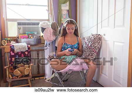 Teenager using smartphone on lazy chair in bedroom View Large Photo Image Stock Photo - Teenager using smartphone on lazy chair in bedroom. Fotosearch