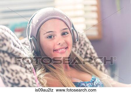 Teenager with earphones smiling on lazy chair View Large Photo Image Stock Photo - Teenager with earphones smiling on lazy chair. Fotosearch