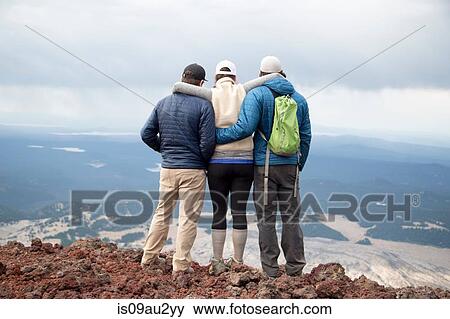 Stock Photo - Three friends standing at the summit of South Sister volcano, looking at view, Bend, Oregon, USA. Fotosearch