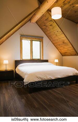 Vaulted Ceiling And Double Bed Below Window In Modern Bedroom Stock Photography