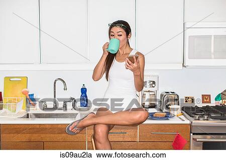 Woman having coffee, using smartphone in kitchen View Large Photo Image Stock Image - Woman having coffee, using smartphone in kitchen. Fotosearch