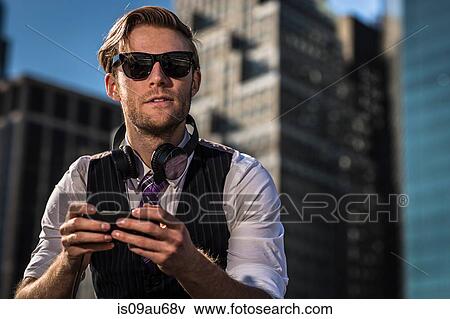 Young businessman in front of office looking away whilst using smartphone, New York, USA View Large Photo Image Stock Photo - Young businessman in front of office looking away whilst using smartphone, New York, USA. Fotosearch