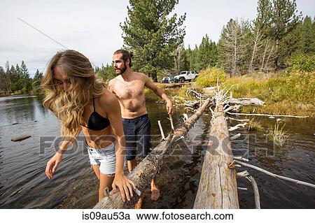 Stock Image - Young couple crossing river, Lake Tahoe, Nevada, USA. Fotosearch