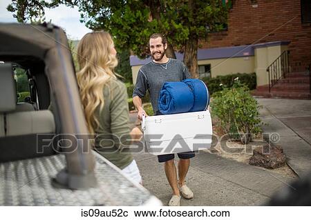 Stock Image - Young couple preparing jeep for road trip. Fotosearch