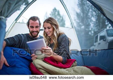 Young couple reading digital tablet in tent, Lake Tahoe, Nevada, USA View Large Photo Image Stock Photo - Young couple reading digital tablet in tent, Lake Tahoe, Nevada, USA. Fotosearch