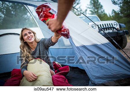 Young couple sharing snacks whilst camping, Lake Tahoe, Nevada, USA View Large Photo Image Stock Photo - Young couple sharing snacks whilst camping, Lake Tahoe, Nevada, USA. Fotosearch