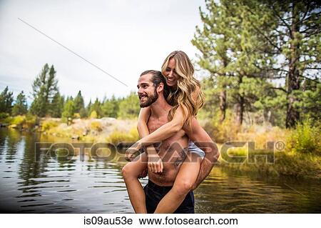 Stock Image - Young man giving girlfriend piggyback in river, Lake Tahoe, Nevada, USA. Fotosearch