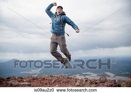 Stock Image - Young man jumping for joy at the summit of South Sister volcano, Bend, Oregon, USA. Fotosearch
