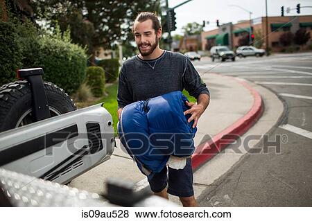 Stock Photo - Young man loading jeep for road trip. Fotosearch