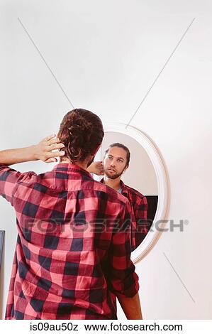 Stock Photo - Young man looking in mirror, rear view. Fotosearch