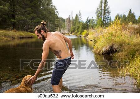 Young man paddling with dog in river, Lake Tahoe, Nevada, USA View Large Photo Image Stock Image - Young man paddling with dog in river, Lake Tahoe, Nevada, USA. Fotosearch
