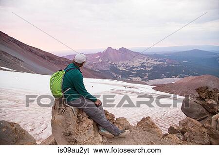 Young man sitting at the summit of South Sister volcano, Bend, Oregon, USA View Large Photo Image Stock Photograph - Young man sitting at the summit of South Sister volcano, Bend, Oregon, USA. Fotosearch