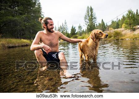 Young man sitting in river petting dog, Lake Tahoe, Nevada, USA View Large Photo Image Stock Image - Young man sitting in river petting dog, Lake Tahoe, Nevada, USA. Fotosearch