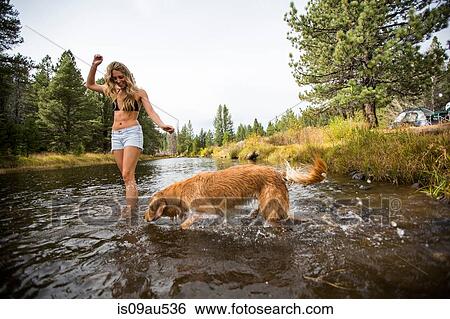 Stock Photograph - Young woman and dog paddling in river, Lake Tahoe, Nevada, USA. Fotosearch