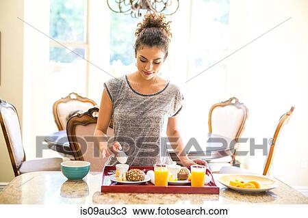 Young woman at home preparing breakfast tray, looking down holding egg View Large Photo Image Stock Image - Young woman at home preparing breakfast tray, looking down holding egg. Fotosearch