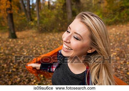Stock Image - Young woman dancing and holding up blanket in autumn forest. Fotosearch