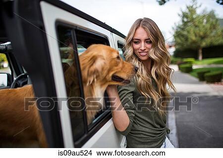 Picture - Young woman petting her dog at jeep window. Fotosearch
