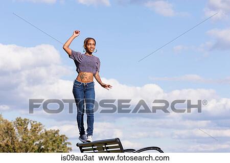 Young woman wearing crop top balancing on back on park bench View Large Photo Image Stock Photograph - Young woman wearing crop top balancing on back on park bench. Fotosearch