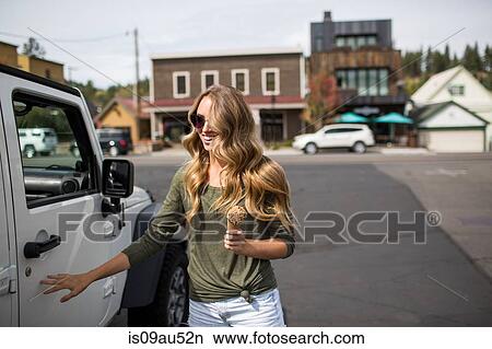 Young woman with long blond hair holding ice cream next to jeep View Large Photo Image Picture - Young woman with long blond hair holding ice cream next to jeep. Fotosearch