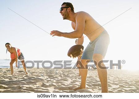 Picture - Adult friends playing American football on Newport Beach, California, USA. Fotosearch