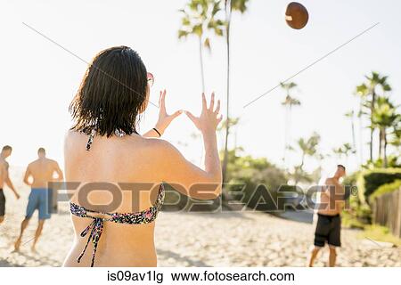 Stock Image - Adult friends playing American football on Newport Beach, California, USA. Fotosearch