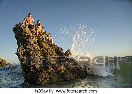 Adult friends sitting on rock formation at Newport Beach, California, USA View Large Photo Image Stock Photo - Adult friends sitting on rock formation at Newport Beach, California, USA. Fotosearch