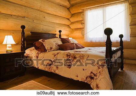 Stock Image - Angled view of antique wooden bed in Eastern white wood log cabin. Fotosearch