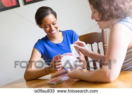 Angled view of young women sitting at dining table playing cards smiling View Large Photo Image Stock Image - Angled view of young women sitting at dining table playing cards smiling. Fotosearch