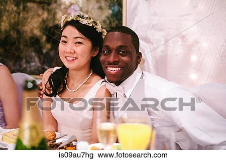 Bride and bridegroom at wedding reception sitting side by side looking at camera smiling View Large Photo Image Stock Image - Bride and bridegroom at wedding reception sitting side by side looking at camera smiling. Fotosearch
