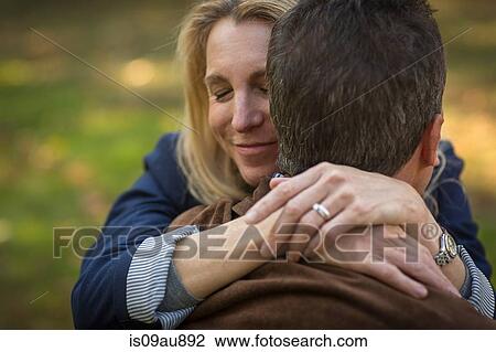 Stock Image - Close up of romantic mature couple hugging in garden. Fotosearch