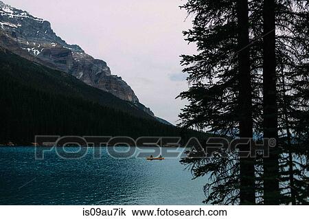 Stock Image - Couple in canoe on Moraine lake, looking at camera, Banff National Park, Alberta Canada. Fotosearch